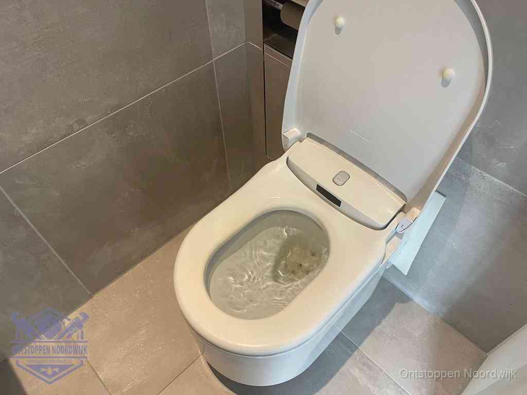 Een toiletpot vol troebel water met drijvend papier en restanten, de meest voorkomende oorzaak van een verstopte wc in Noordwijk