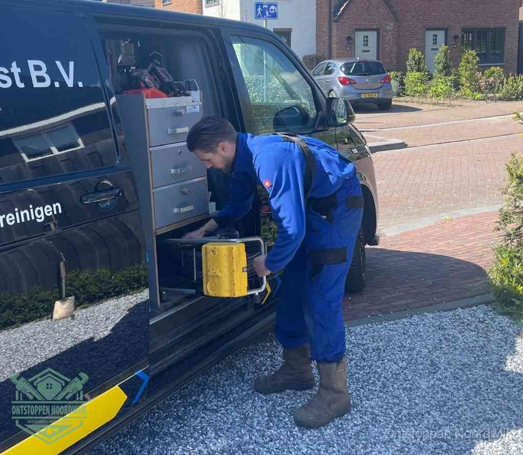 Een monteur pakt buiten op de oprit gereedschap uit de bedrijfsbus, het moment om een professional in te schakelen voor een verstopte afvoer in Noordwijk