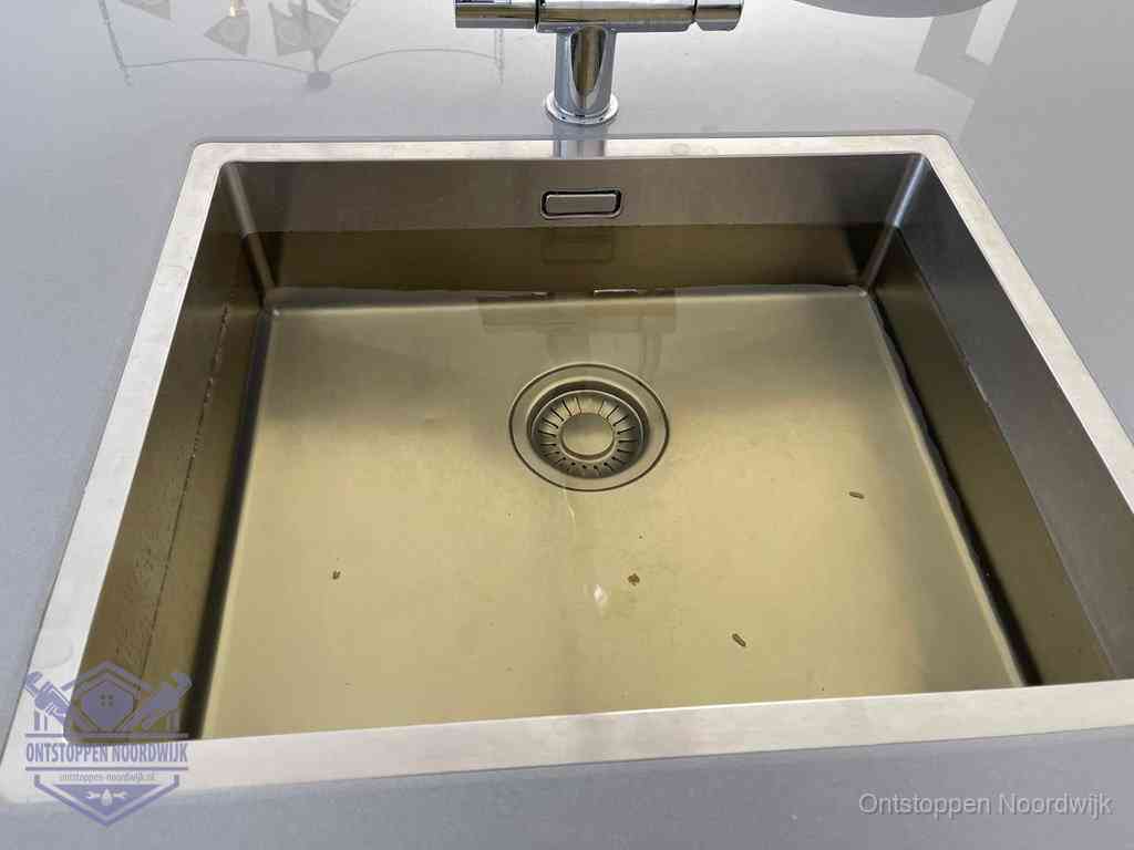 Stilstaand water in een rvs spoelbak dat niet wegloopt, een duidelijk signaal van een gootsteenverstopping in Noordwijk