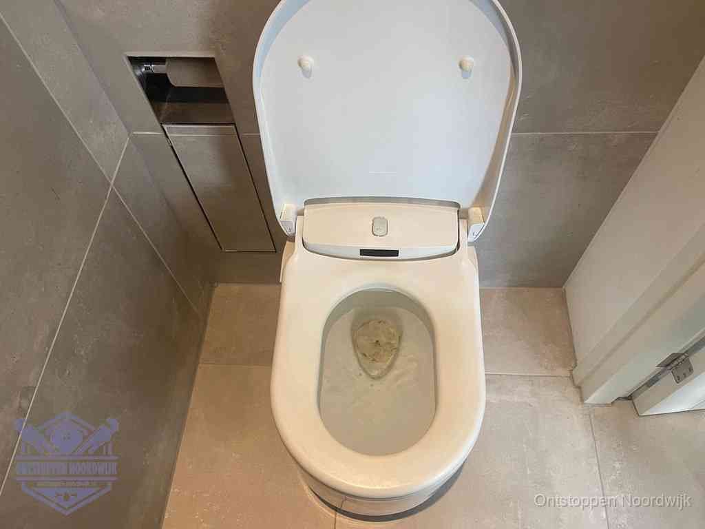 Een wit hangtoilet waarin een prop wc-papier op het water blijft drijven, een duidelijk signaal van een verstopte wc in Noordwijk