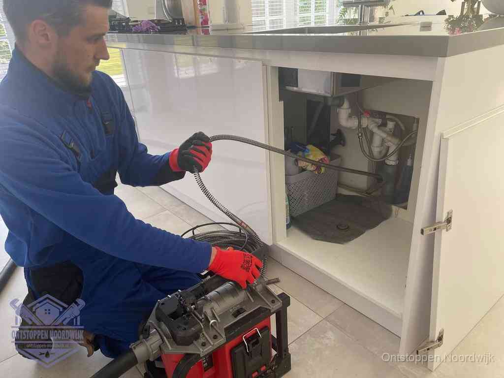 Een monteur reinigt de keukenafvoer grondig met een veermachine om terugkerende gootsteenverstoppingen te voorkomen in Noordwijk