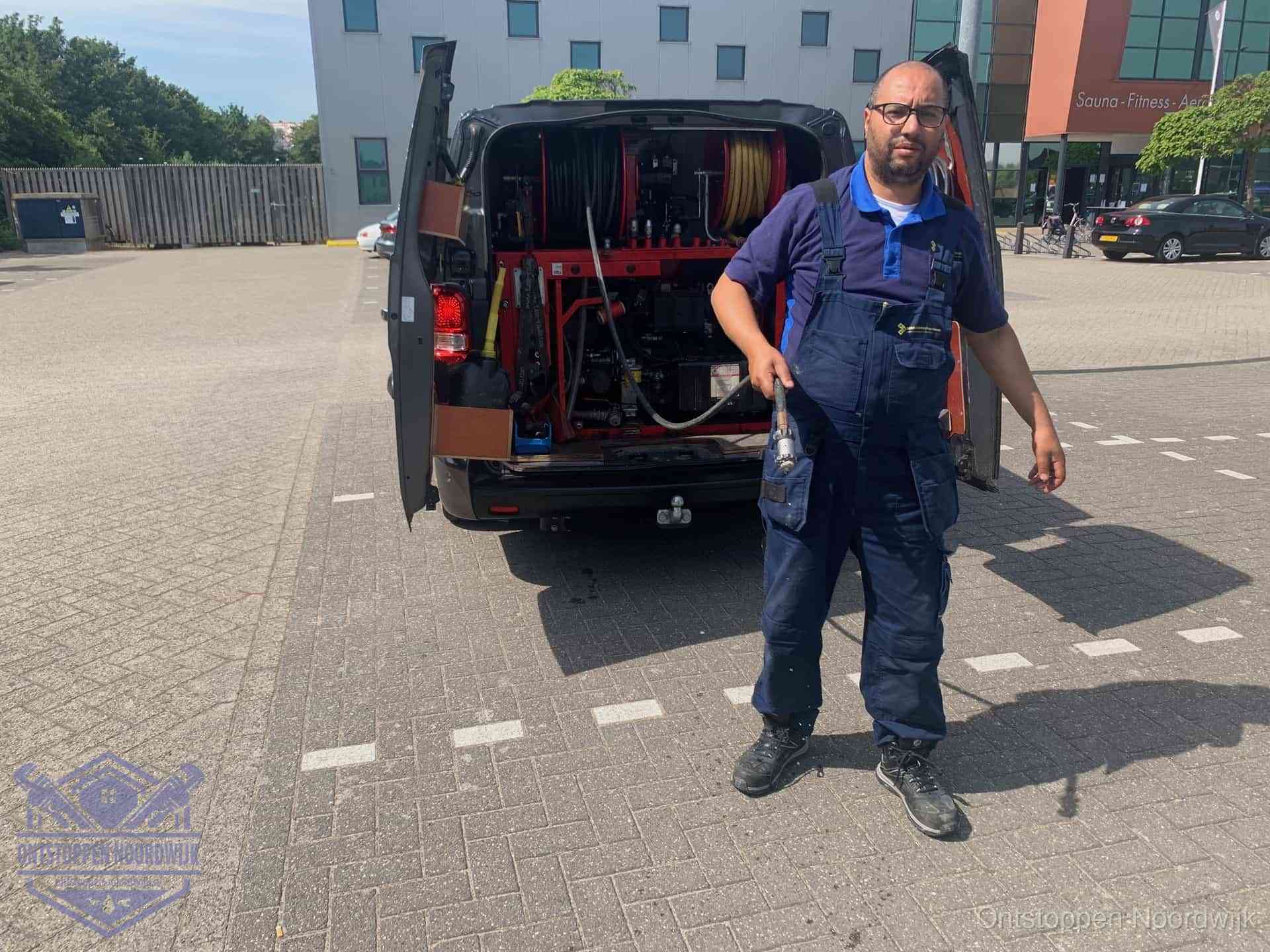Een monteur bij zijn bestelbus met een hogedruk- en rioolreinigingsunit, klaar om de oorzaak van terugkerende wc-verstoppingen aan te pakken in Noordwijk