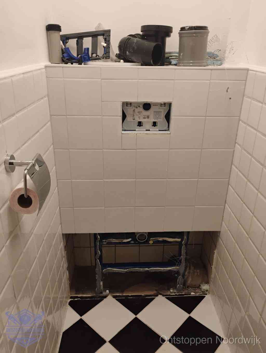 Een toiletruimte waar het hangtoilet en de inbouwreservoir-onderdelen zijn vrijgelegd voor onderhoud, periodiek nazicht voorkomt een wc-verstopping in Noordwijk